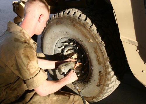 Military service member using air compressor on military vehicle
