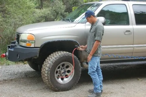 Person using air compressor on tire off road