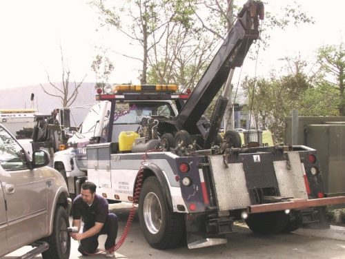 Tow truck driver using air compressor on car